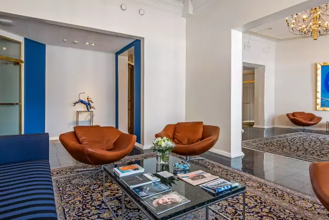 Toimisto sinisellä sohvalla ja ruskealla tuolilla